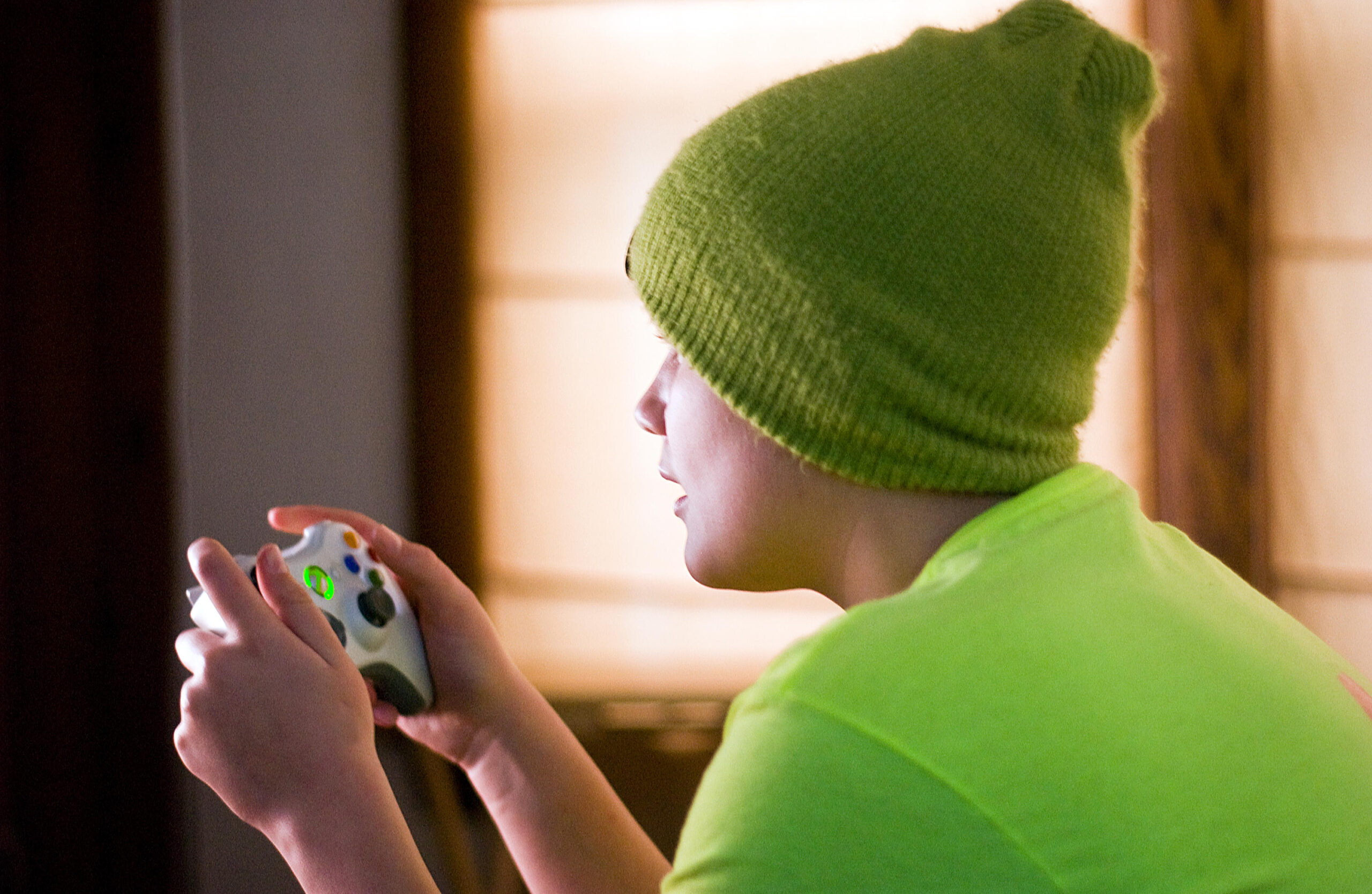 a child in a green cap and green shirt playing 007 First Light on his X Box